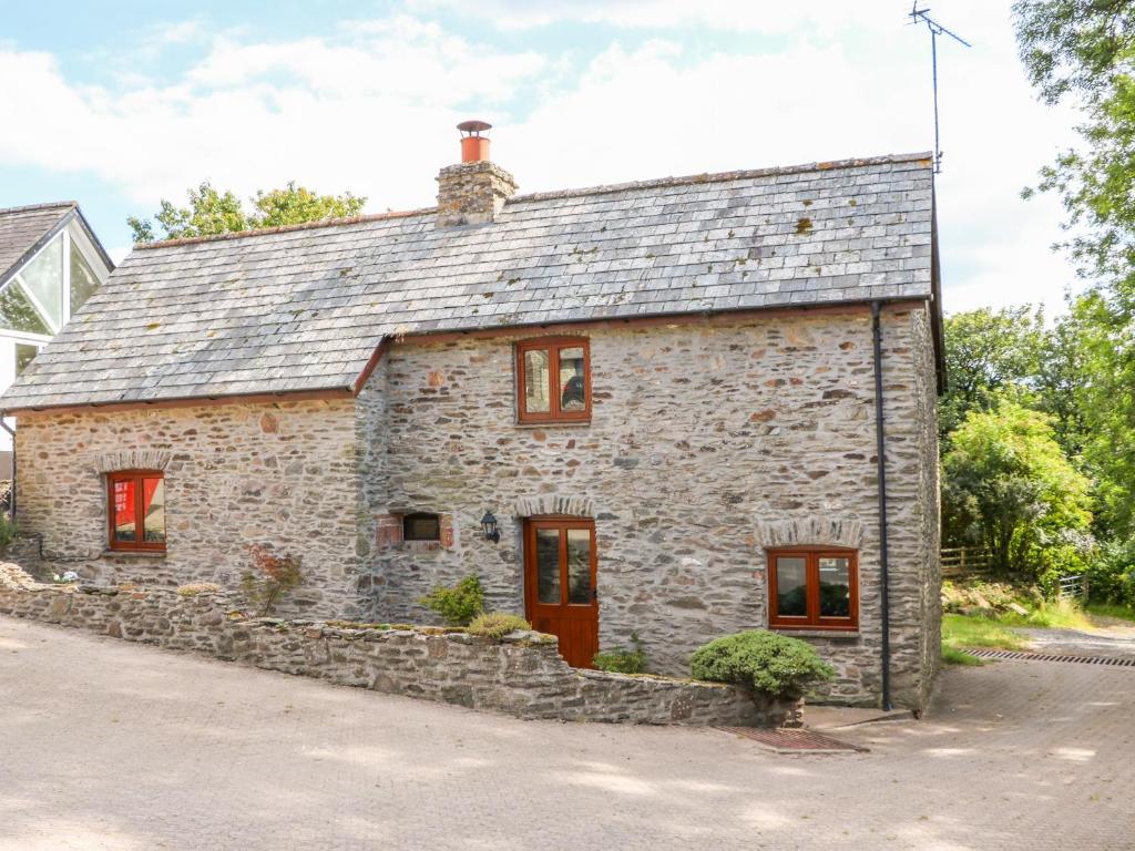 una vecchia casa in pietra con porte e finestre rosse di Great Bradley Cottage a Minehead