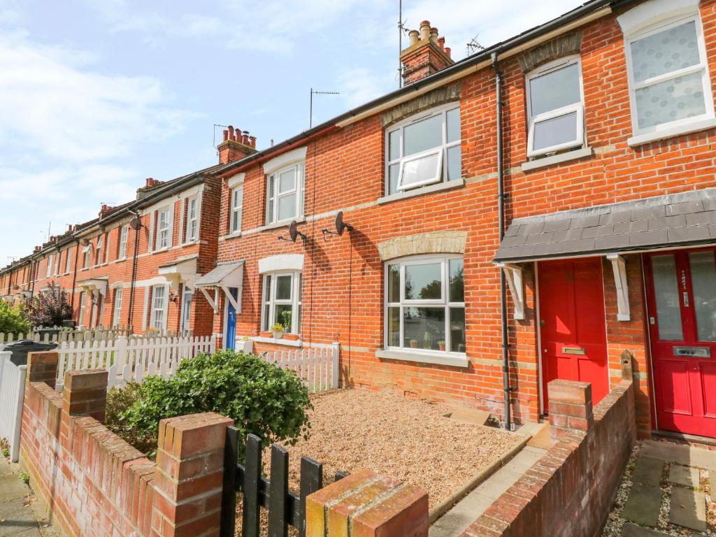 una casa de ladrillo rojo con puerta roja en Sea View Cottage, en Frinton-on-Sea