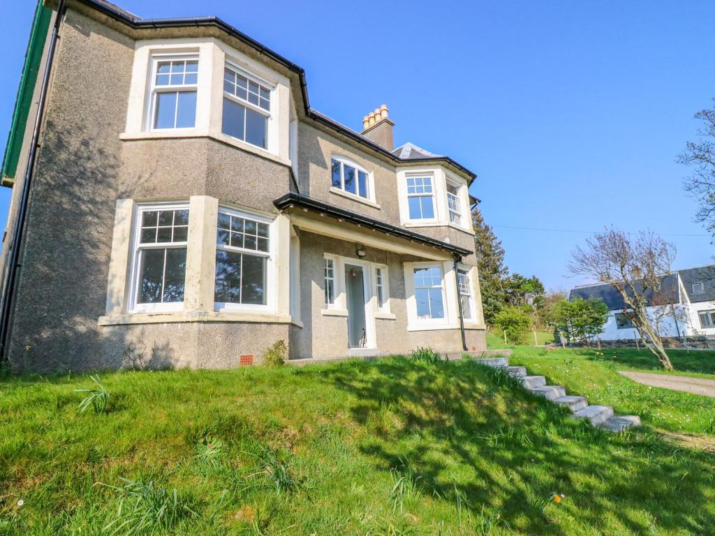 a large brick house on a green lawn at Tullochgorm in Arisaig