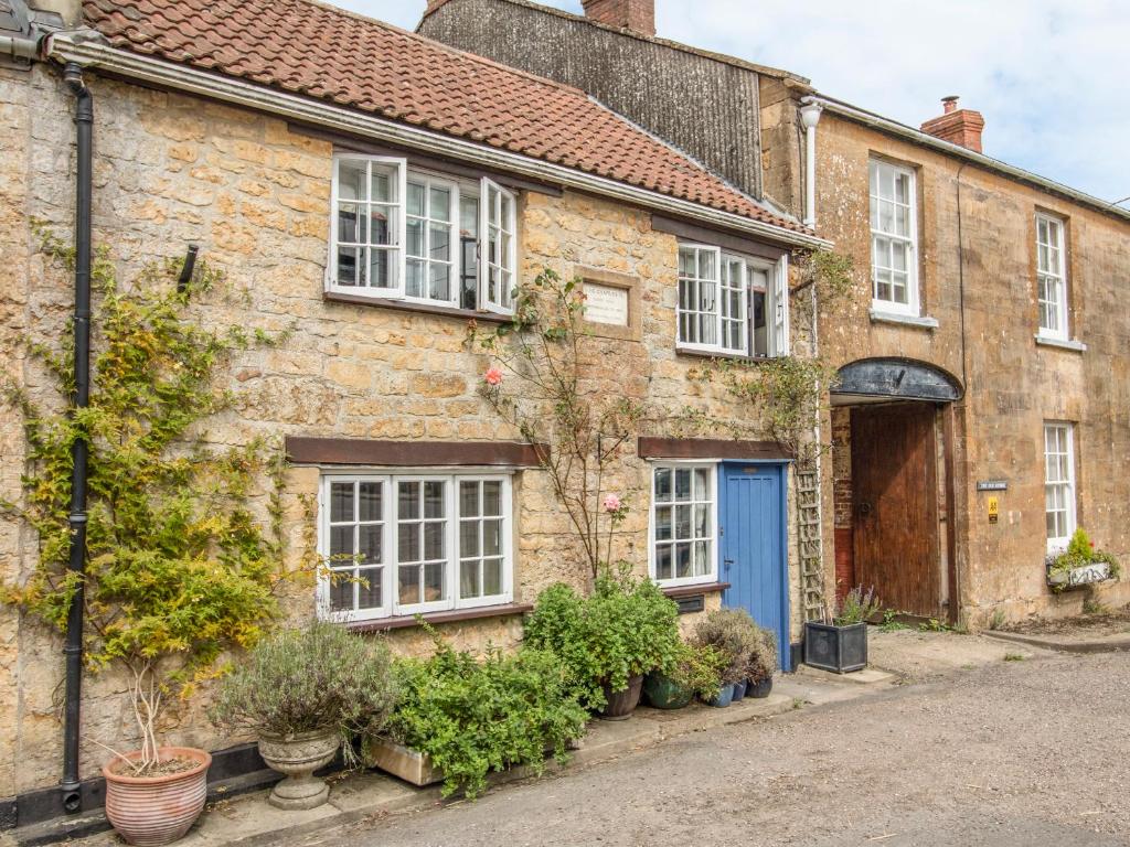 an old brick house with a blue door at King Charles Cottage in Beaminster