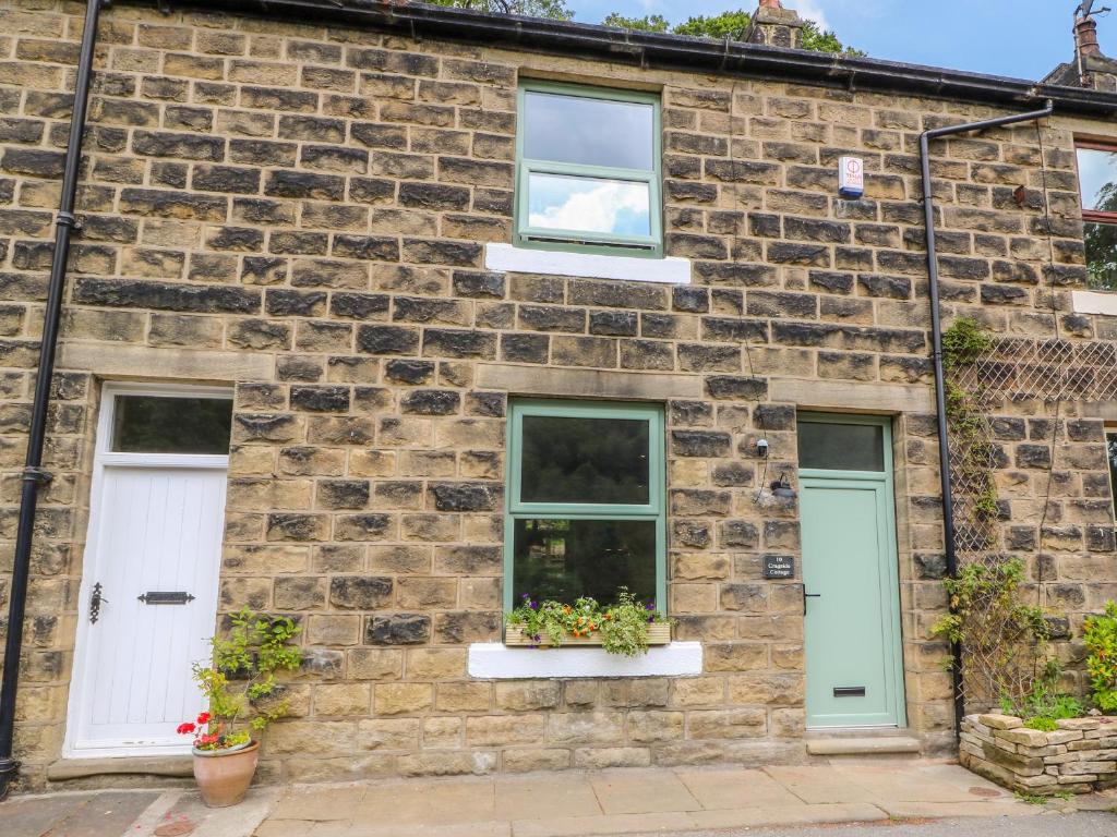 a brick house with two white doors and two windows at Cragside Cottage in Hebden Bridge