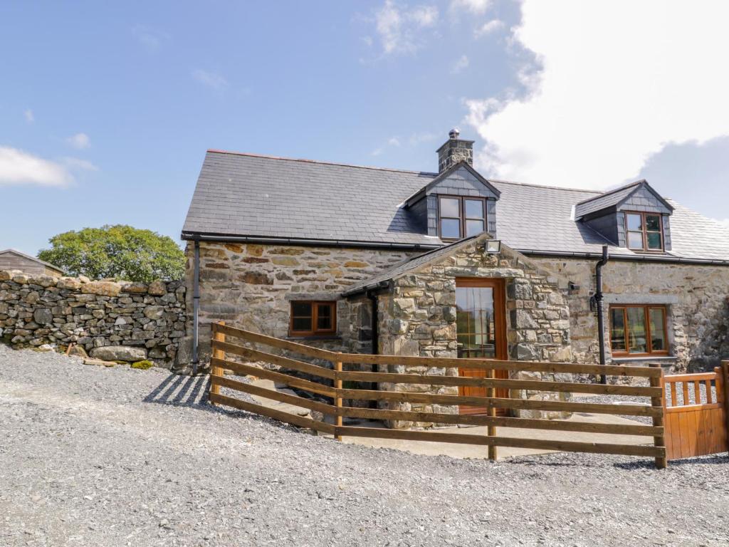 a stone house with a wooden fence in front of it at Yr Hen Stabal in Blaenau-Ffestiniog