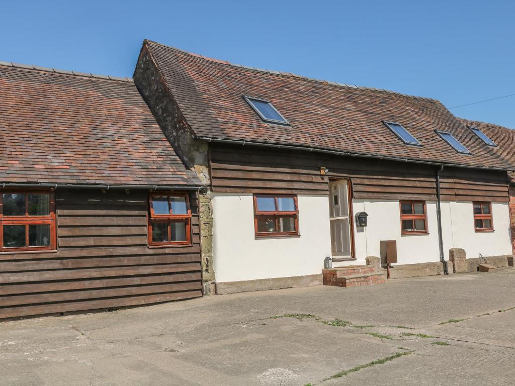 ein altes weißes Haus mit Holzwänden und Fenstern in der Unterkunft Old Hall Barn 3 in Church Stretton