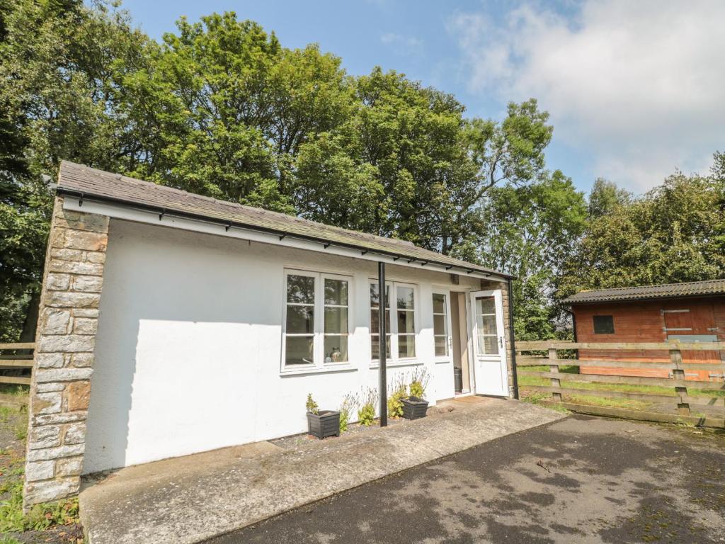 un petit garage blanc avec une clôture dans l'établissement Vallum Kiosk, à Hexham