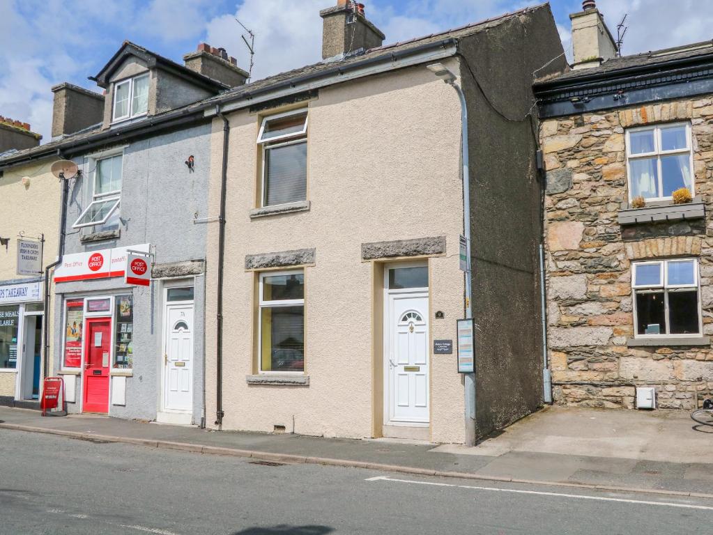 an old brick building with a red door on a street at Molly's Cottage in Grange Over Sands