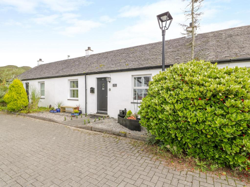 uma casa branca com uma luz de rua em frente em Grebe Cottage em Oban