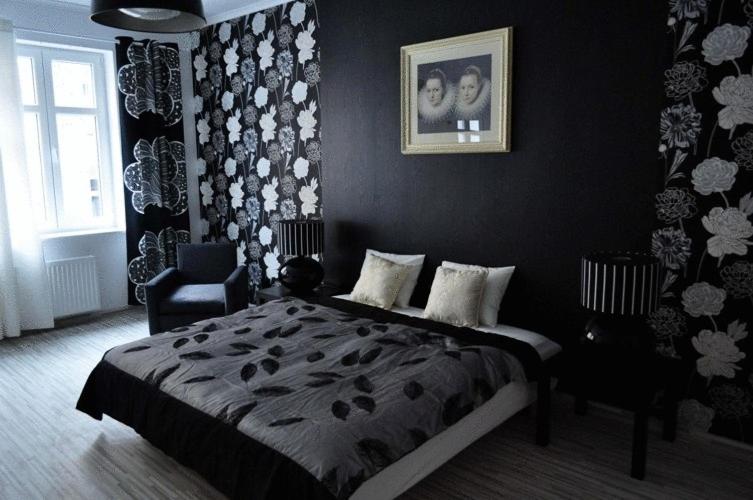 a black bedroom with a bed and a chair at Artrooms in Poznań