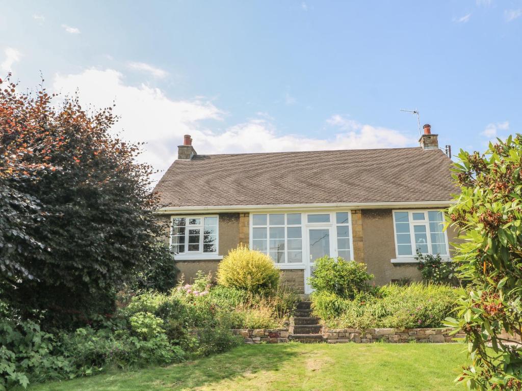 a brick house with white windows in a yard at Ingledene in Highpeak Junction