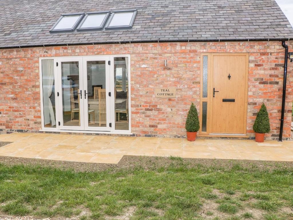 a brick building with a door and a patio at Teal Cottage in Melton Mowbray