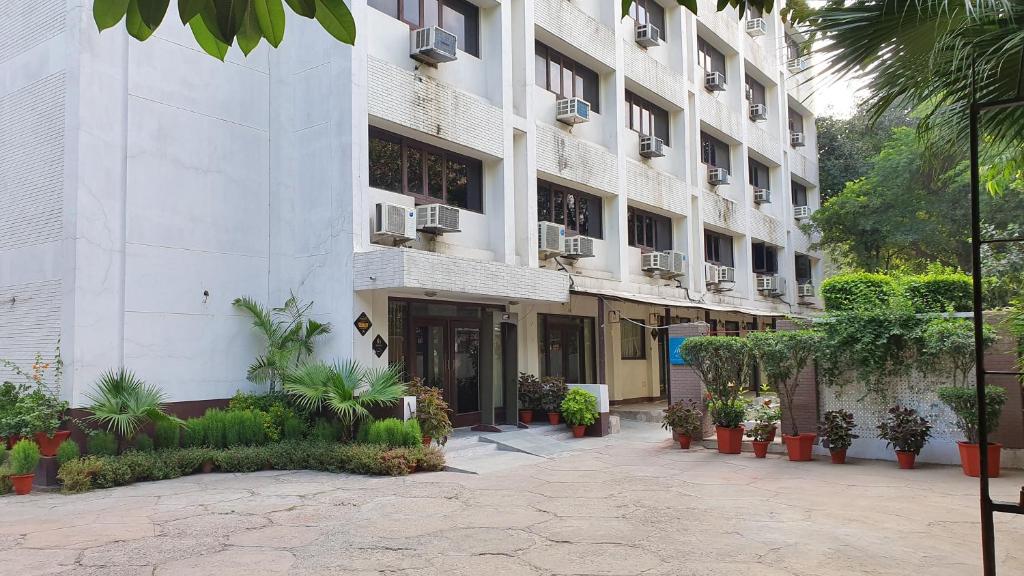 un gran edificio blanco con plantas delante en YWCA International Guest House, en Nueva Delhi
