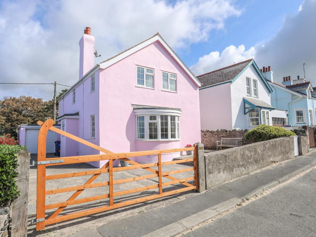 a pink house with a wooden gate in front of it at The Pink House in Rhosneigr