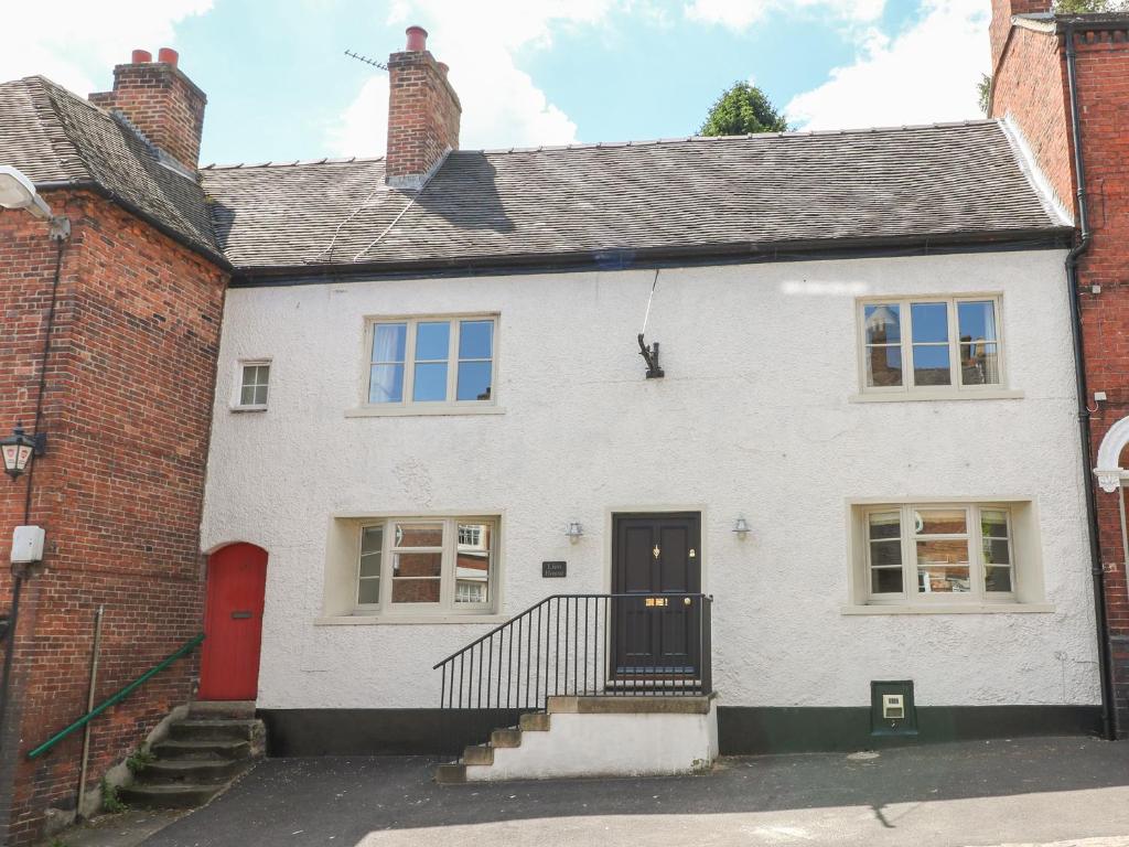 a white house with a red door and brick buildings at Lion House in Ashbourne