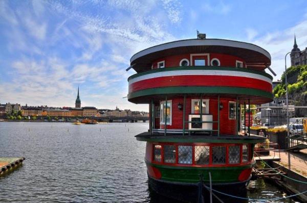 a red and green building sitting in the water at Den Röda Båten in Stockholm