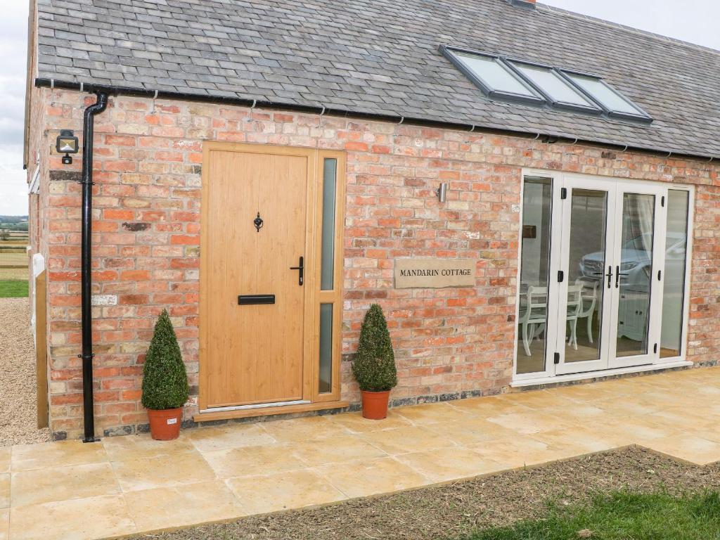 een bakstenen gebouw met een houten deur en ramen bij Mandarin Cottage in Melton Mowbray