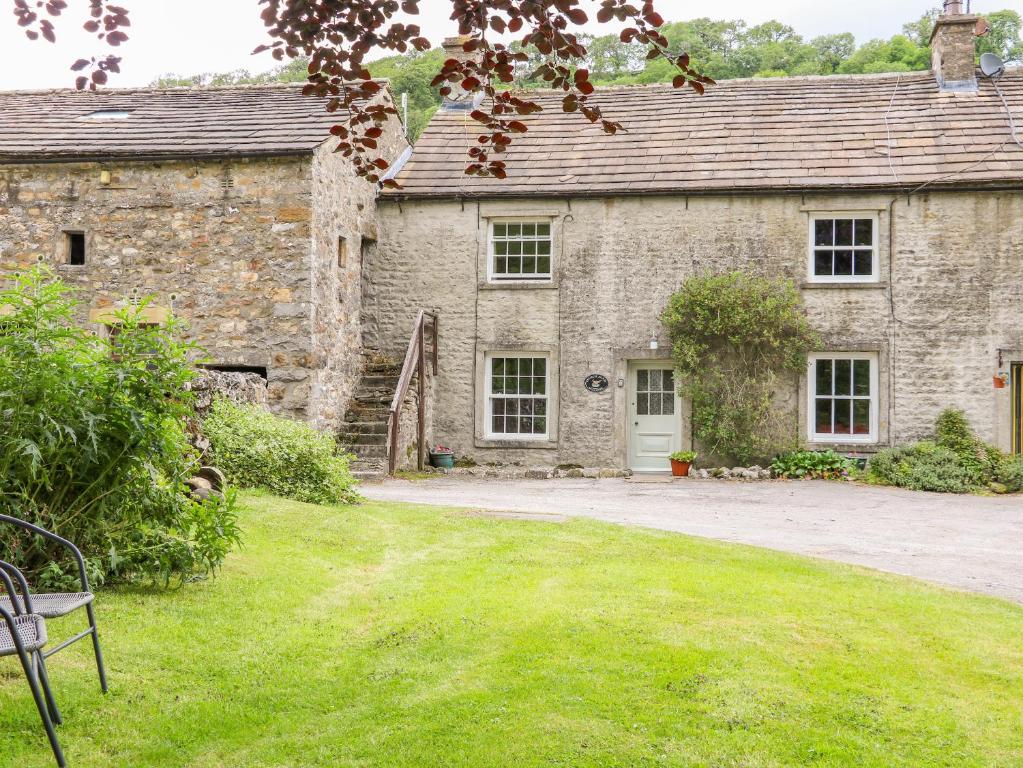 an old stone house with a grass yard at Church Farm Cottage in Skipton