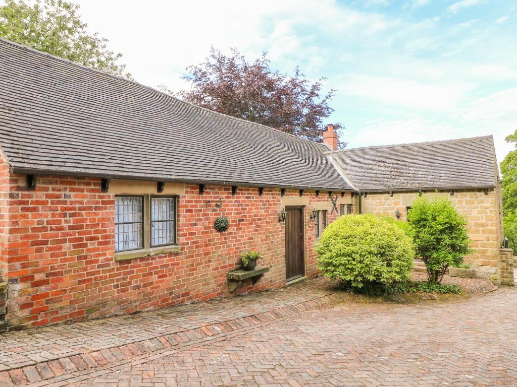 an old brick house with a brick driveway at Woodland Lodge in Alfreton