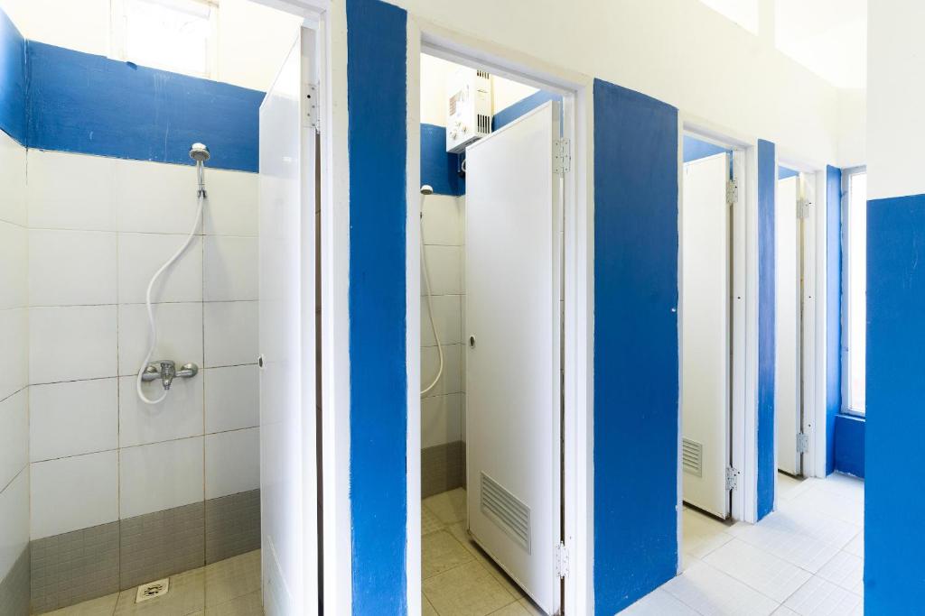 e bagno con doccia e pareti bianche e blu. di RedDoorz Hostel @ Dago 2 a Bandung