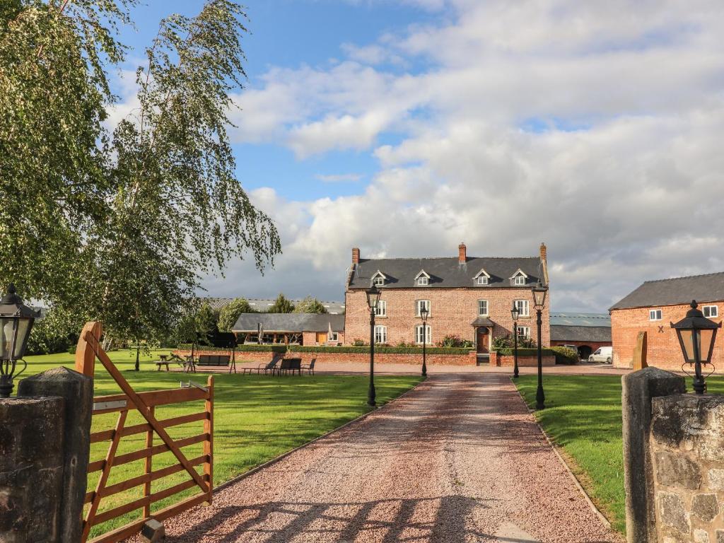 una entrada que conduce a una casa grande con una valla en Rhandregynwen Hall en Llanymynech