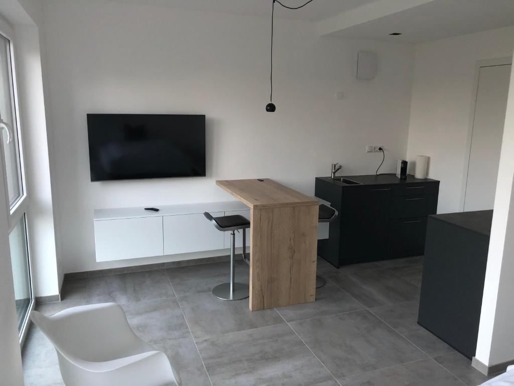 Habitación con mesa y TV en la pared. en Kruft-apps, en Kruft