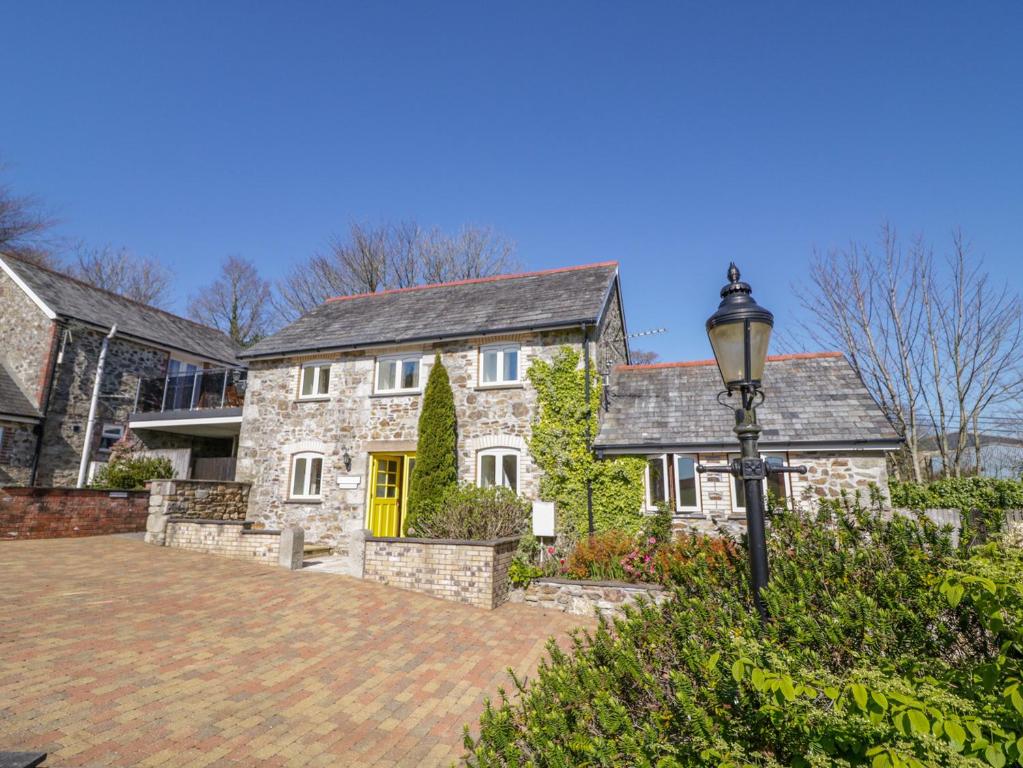 a large stone house with a yellow door at Cornflower Cottage in Saint Columb Major