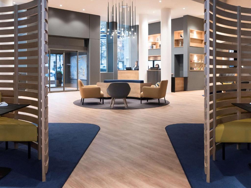 un hall avec des chaises et une table dans un bâtiment dans l'établissement Novotel Château de Versailles, à Versailles