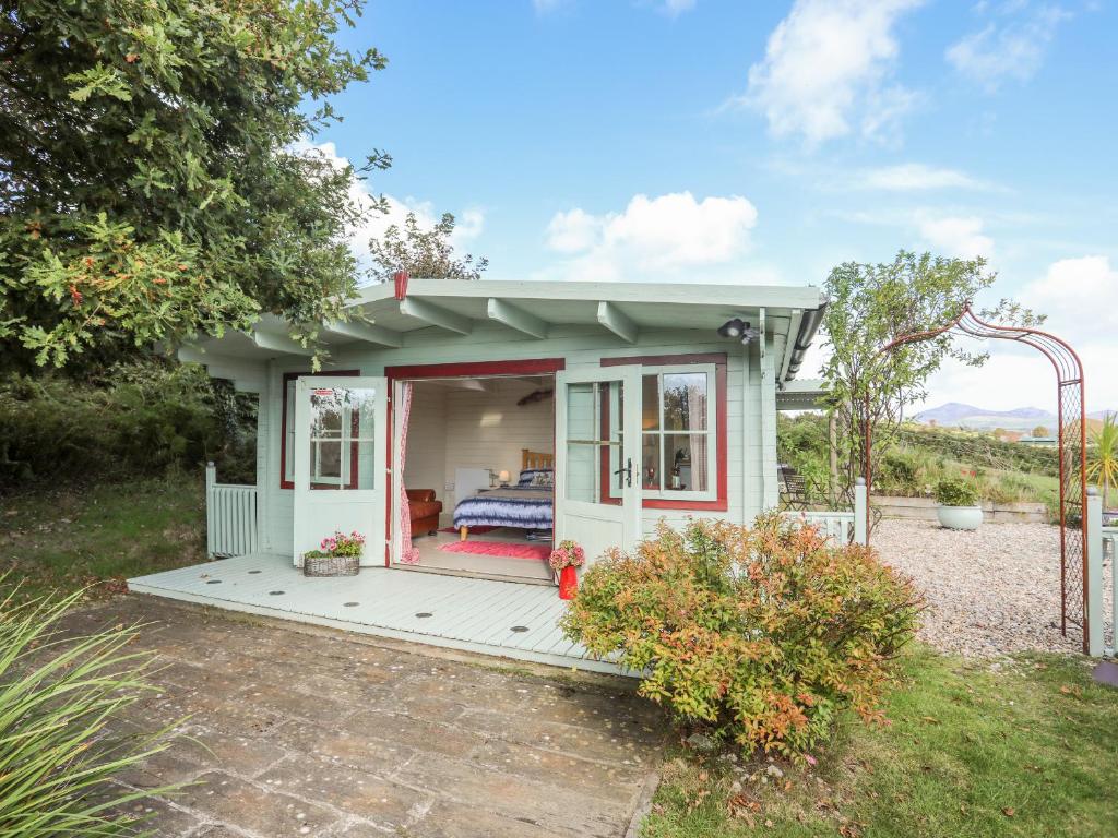 a tiny house with a porch in a garden at Songbird Hideaway in Pwllheli