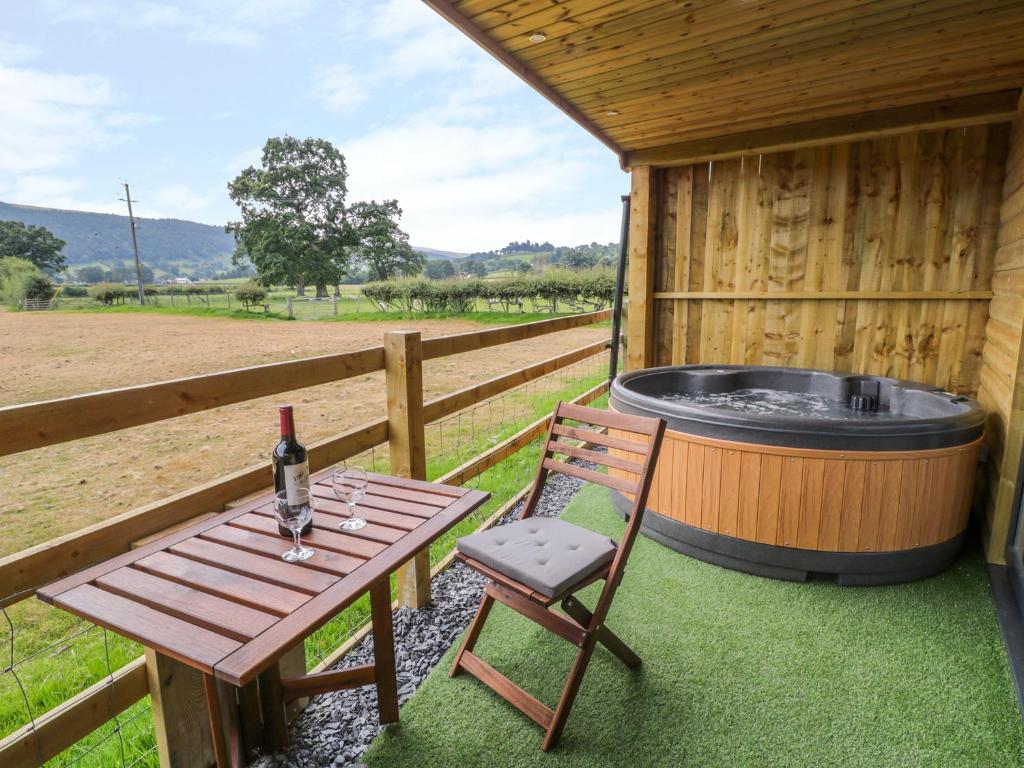 a table and a chair next to a hot tub at Cilan Lodge in Corwen