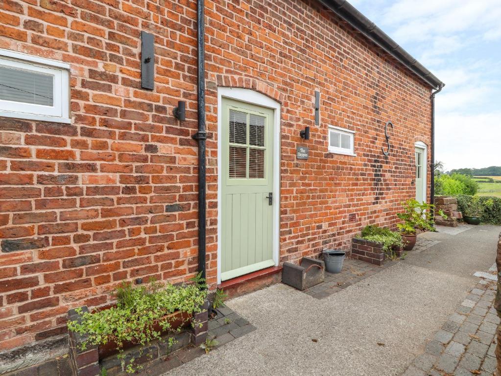 a brick building with a green door on it at The Shippon in Tarporley
