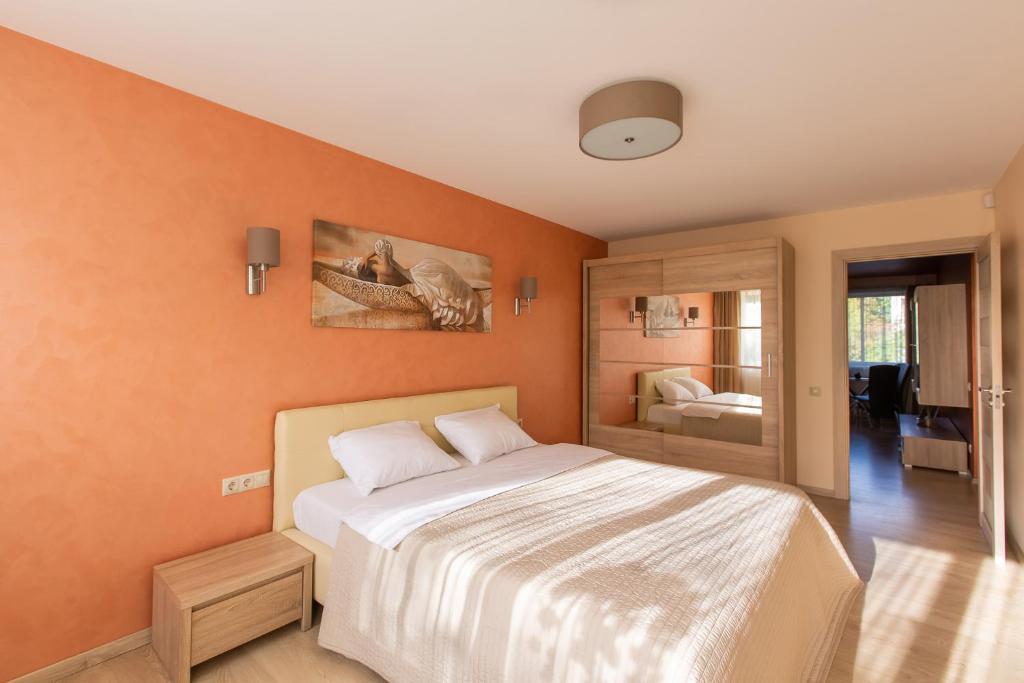 1 dormitorio con 1 cama grande y paredes de color naranja en Audros Apartamentai, en Kaunas