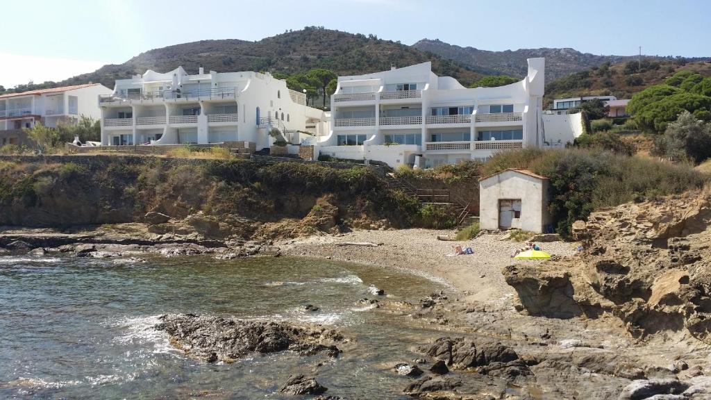 uma grande casa branca num penhasco ao lado de uma praia em carpe diem beach front cat em Port de la Selva