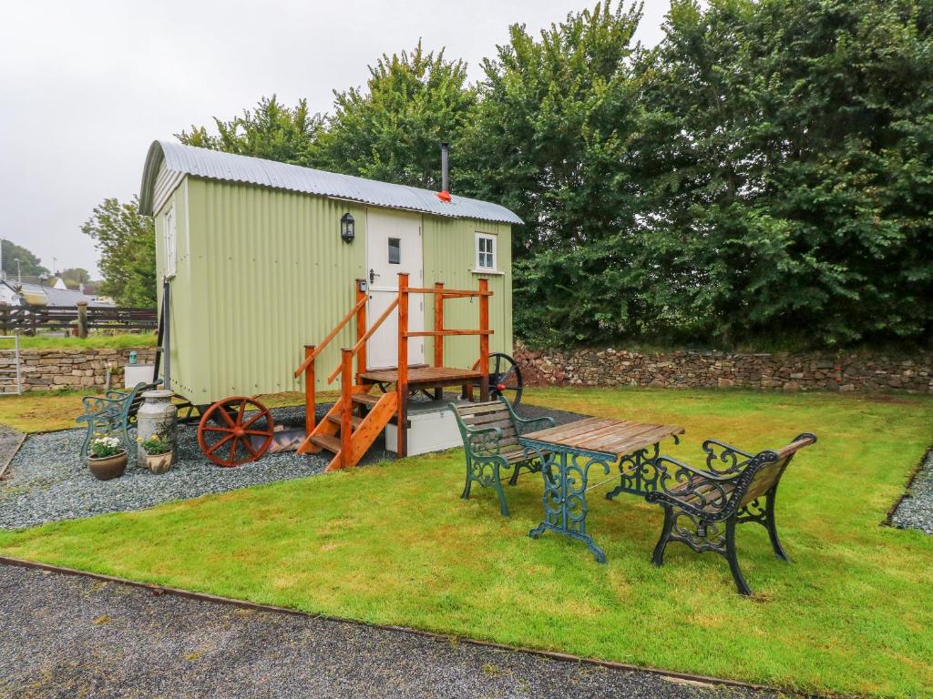 a picnic table and benches in a yard with a shed at Shepherds Hut - The Hurdle in Milford Haven