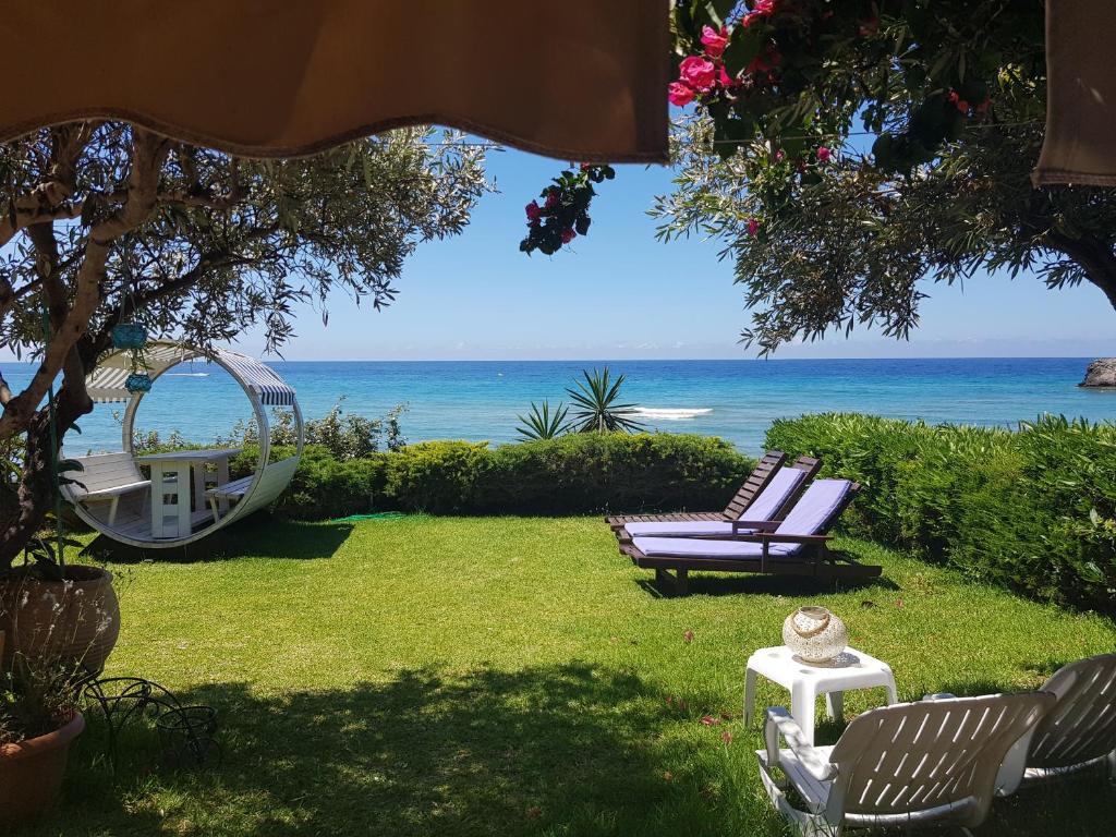 グリファダにあるCorfu Glyfada Beach Apartment 13の椅子2脚とブランコと海のある庭