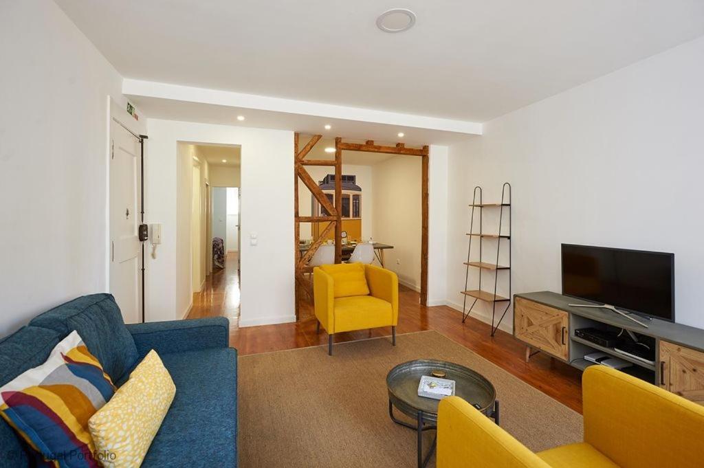 ein Wohnzimmer mit einem blauen Sofa und gelben Stühlen in der Unterkunft Bica Apartment in Lissabon