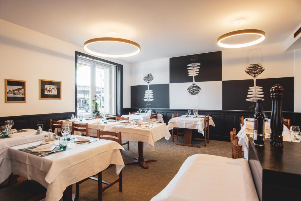 ドレモンにあるHôtel Victoriaの白いテーブルと椅子、チェッカーボードの壁が備わるレストラン