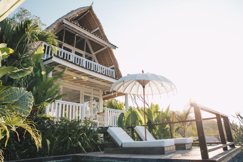 烏魯瓦圖的住宿－White Tortoise Eco Villa's，一个带游泳池的度假胜地和一个带遮阳伞的房子