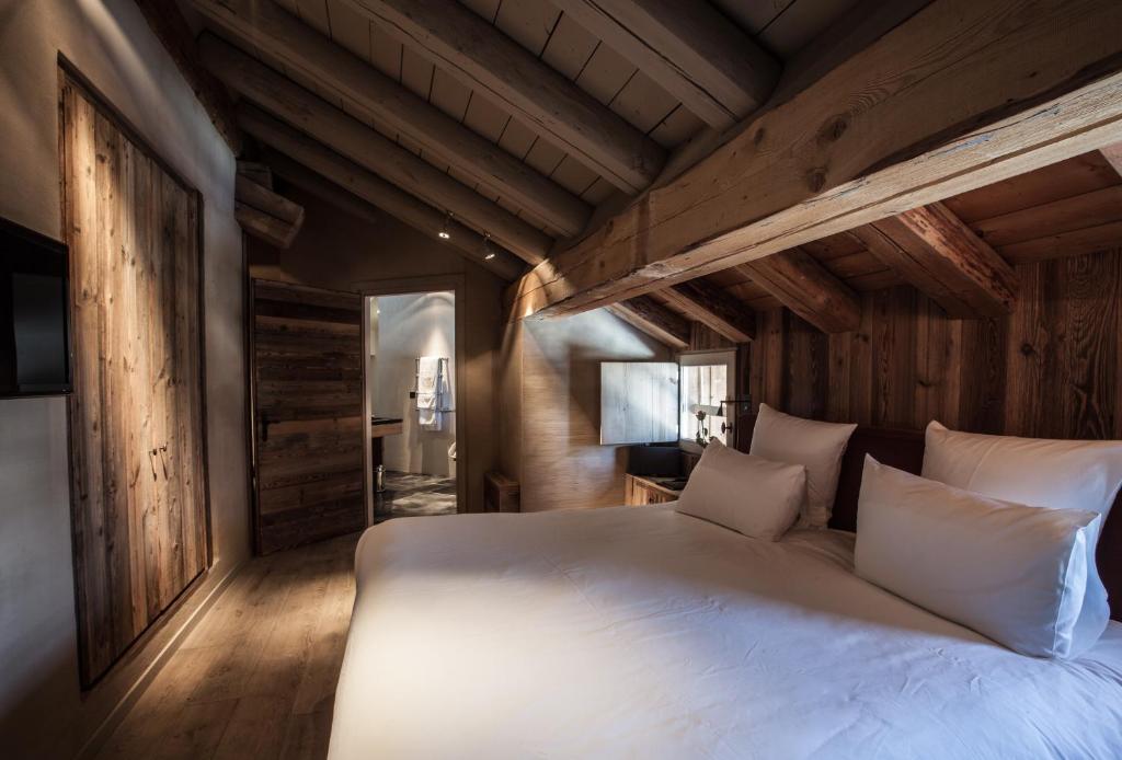 a large white bed in a room with wooden walls at Zannier Hotels Le Chalet in Megève