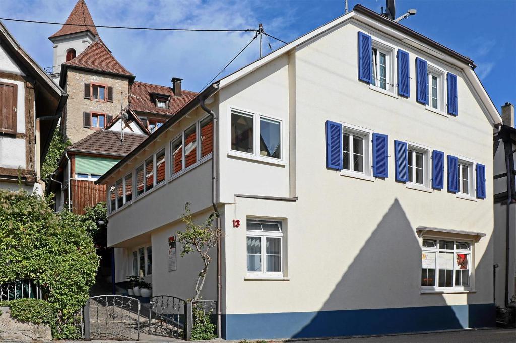 a white house with blue shutters on a street at Mariposa Apartamento in Efringen-Kirchen