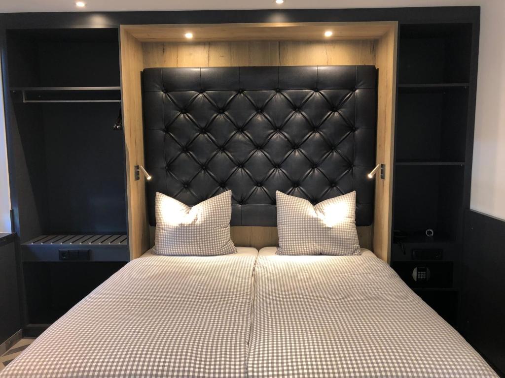 a bed with a black headboard and two white pillows at Munich Deluxe Hotel in Munich