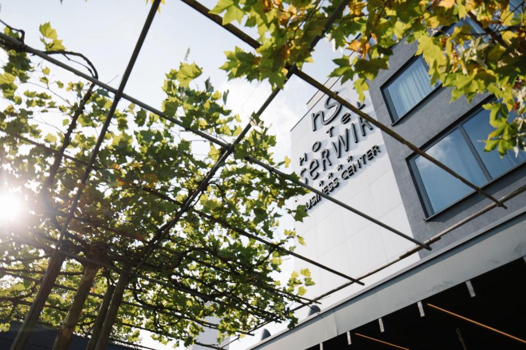 een bord aan de zijkant van een gebouw met bomen bij Serwir Hotel in Sint-Niklaas