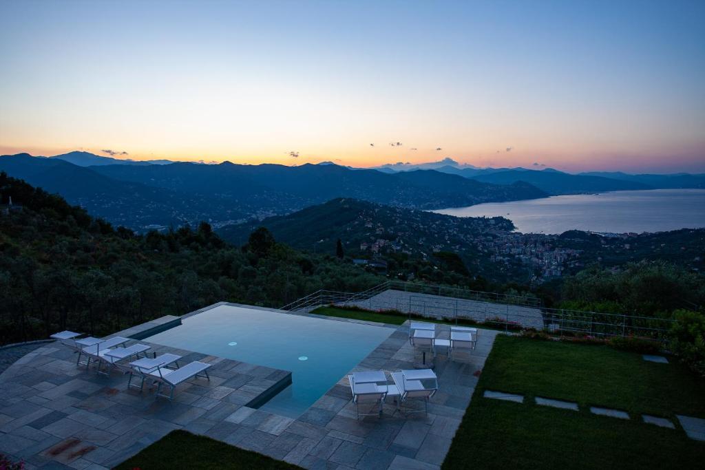 a swimming pool with white chairs and a sunset at Il Leccio - Luxury Resort Portofino Monte in Santa Margherita Ligure