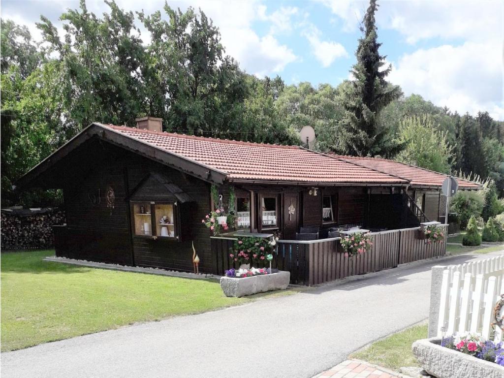 una pequeña casa de madera con una valla blanca en Gerda's Ferienhäuser en Eppenschlag