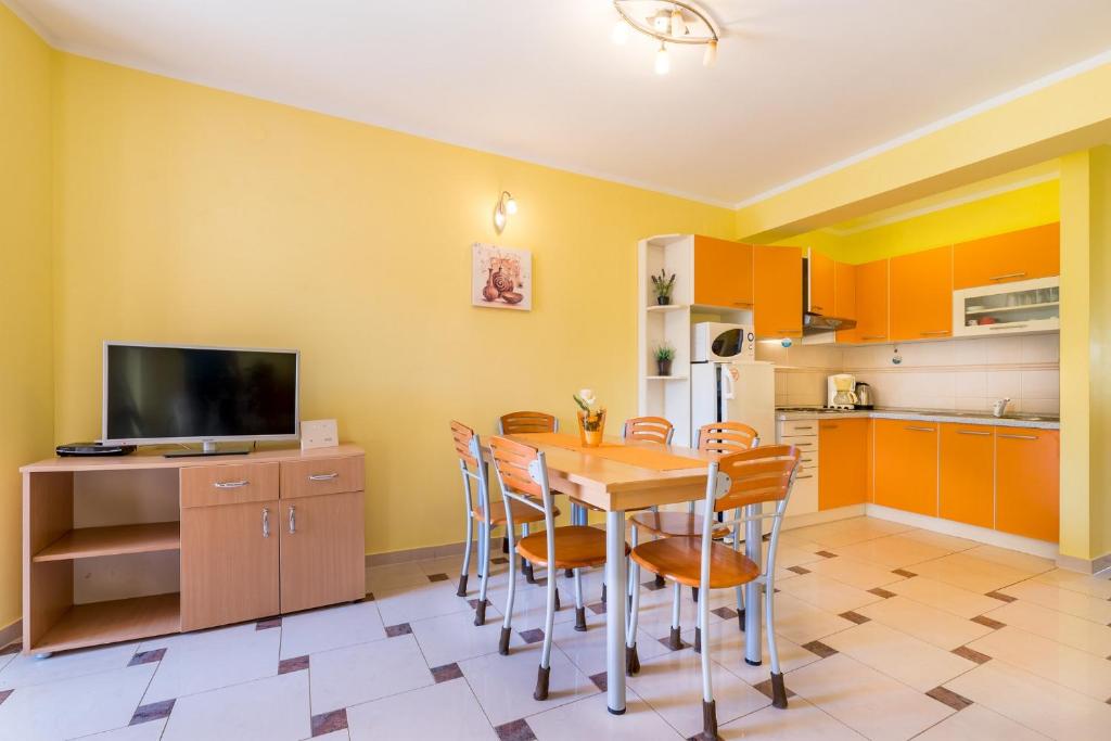 a kitchen with a table and chairs and a television at Apartments Nada in Baška