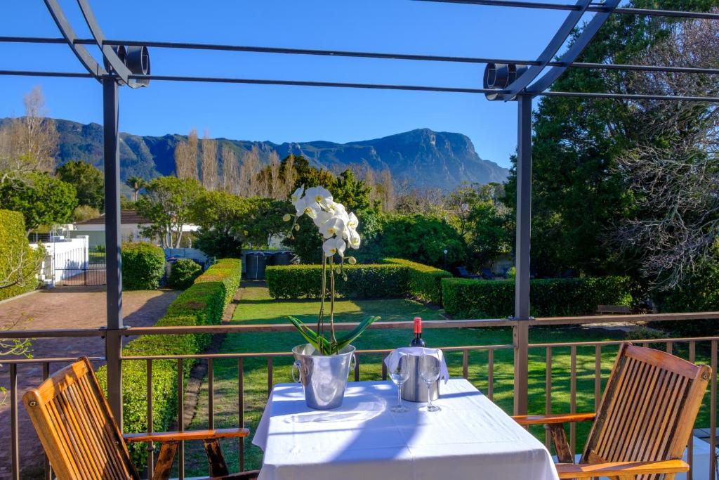 una mesa con un jarrón de flores sentada en un porche en Constantia White Lodge Guest House, en Ciudad del Cabo