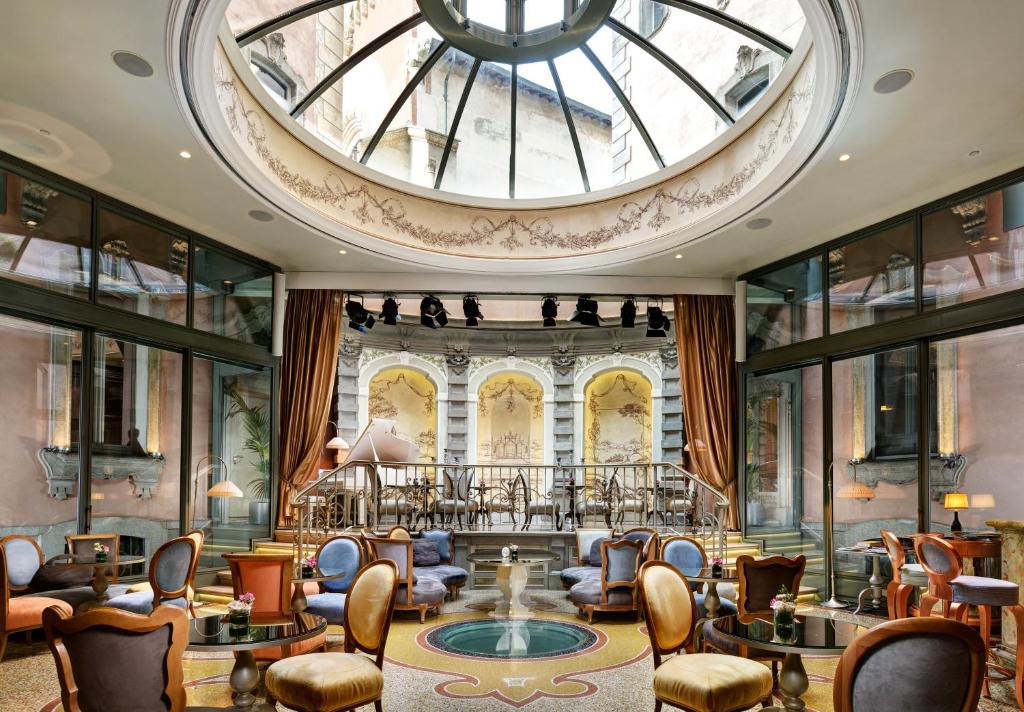 a lobby with chairs and a large ceiling at Château Monfort - Relais & Châteaux in Milan