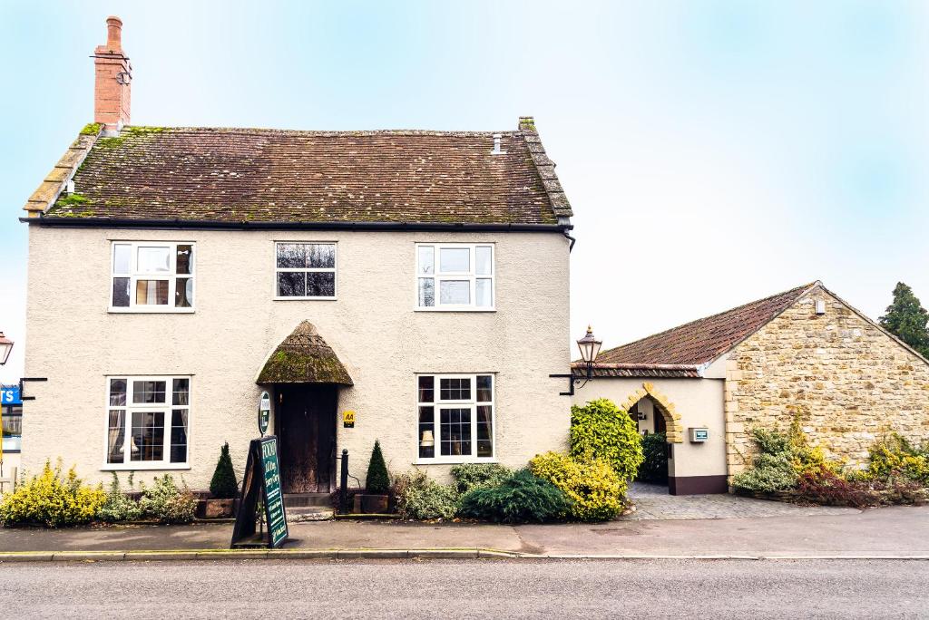 une grande maison blanche avec un panneau devant elle dans l'établissement The Half Moon Inn and Country lodge, à Yeovil