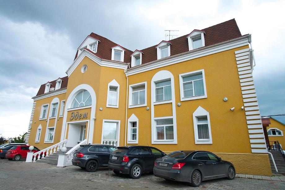 un edificio amarillo con coches estacionados frente a él en Edem Hotel, en Zelenograd