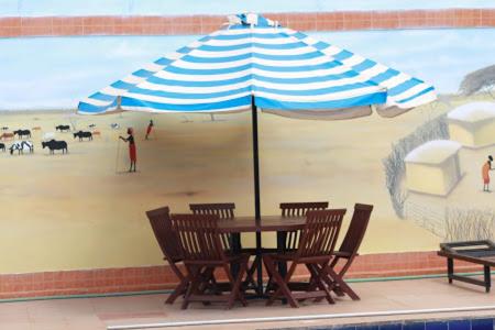 a table with chairs and an umbrella on a beach at Miryams Village Inn Safari Lodge in Sultan Hamud