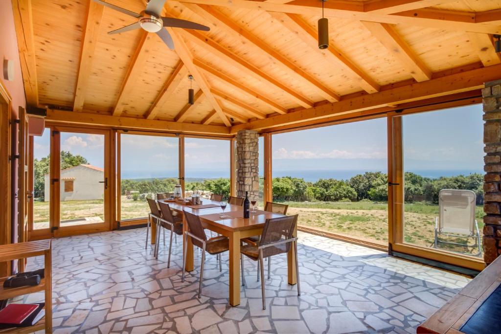 a dining room with a table and chairs and windows at Holiday home Verin in Mali Lošinj