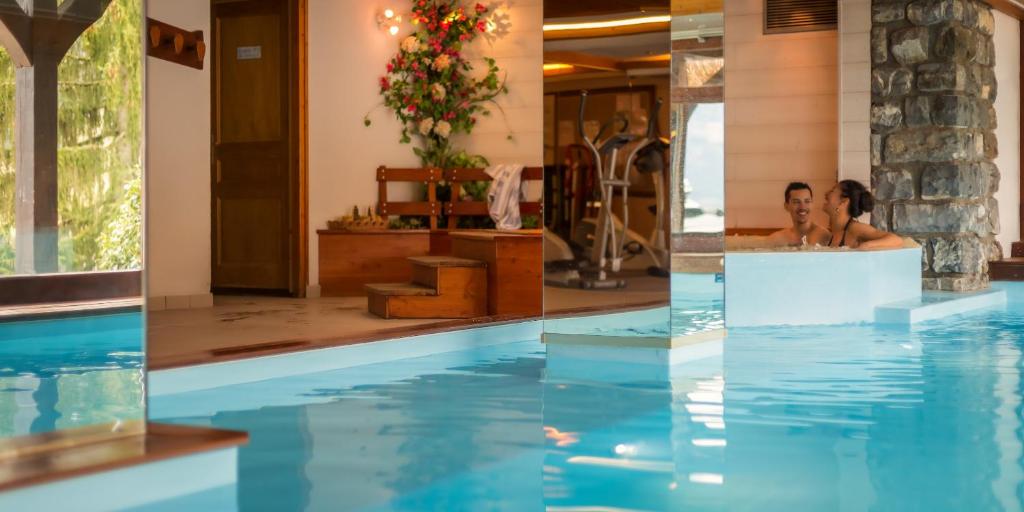 two people sitting in a swimming pool in a hotel at Hotel & Spa Le Dahu in Morzine