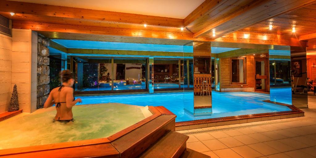 a man in a swimming pool in a house at Hotel & Spa Le Dahu in Morzine